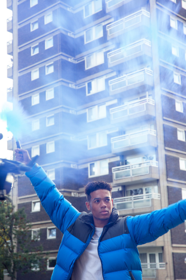 Man in blue puffer jacket holding smoke bombs