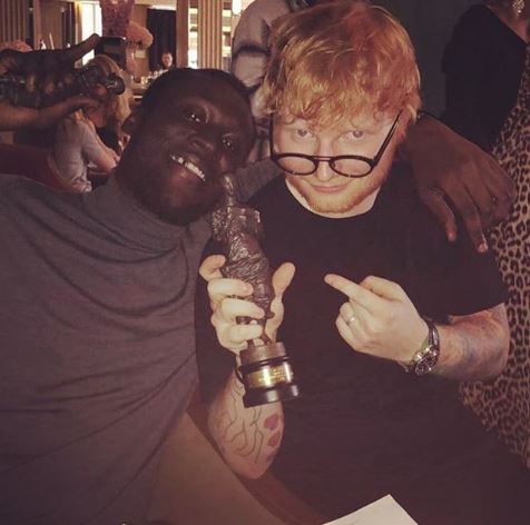 Stormzy in a grey turtleneck jumper next to ed sheeran