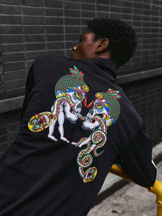 Man wearing a Adidas x Tanaami hoodie with art on the back.