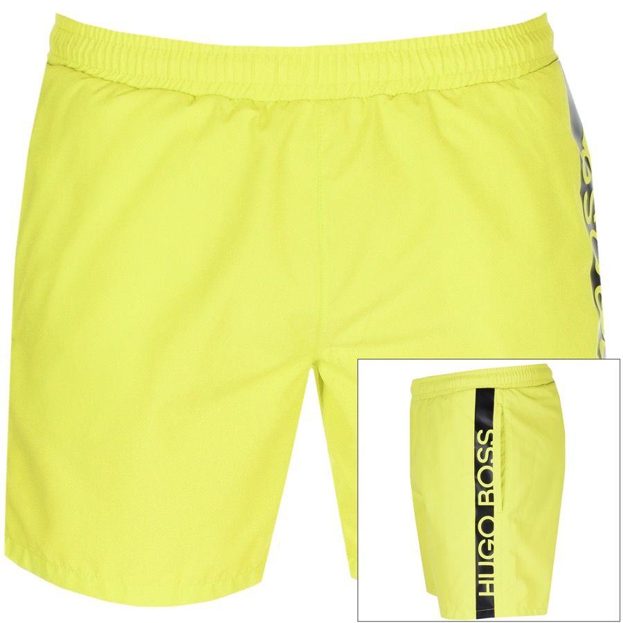 A pair of Hugo Boss swimming shorts in bright neon yellow with a black HUGO BOSS logo running down one side