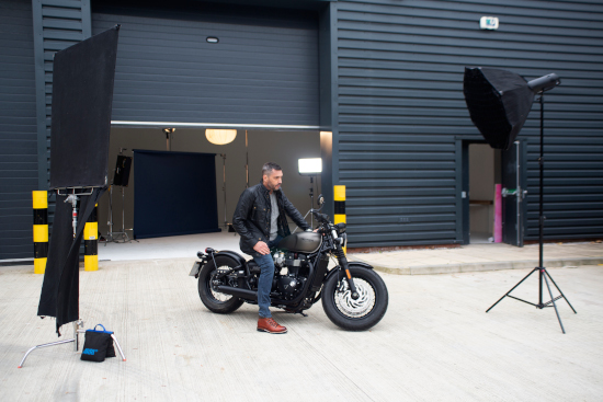 A man is sat on a motorbike surrounded by crew lights. 