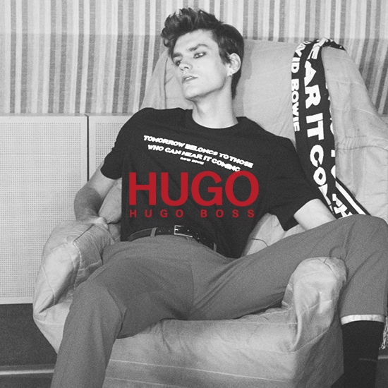A man is lounging on a chair wearing a Hugo t-shirt